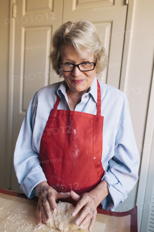 Older woman shaping dough in kitchen