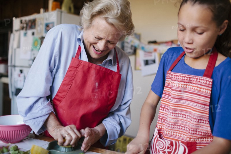 Grandmother and granddaughter squeezing juice in kitchen