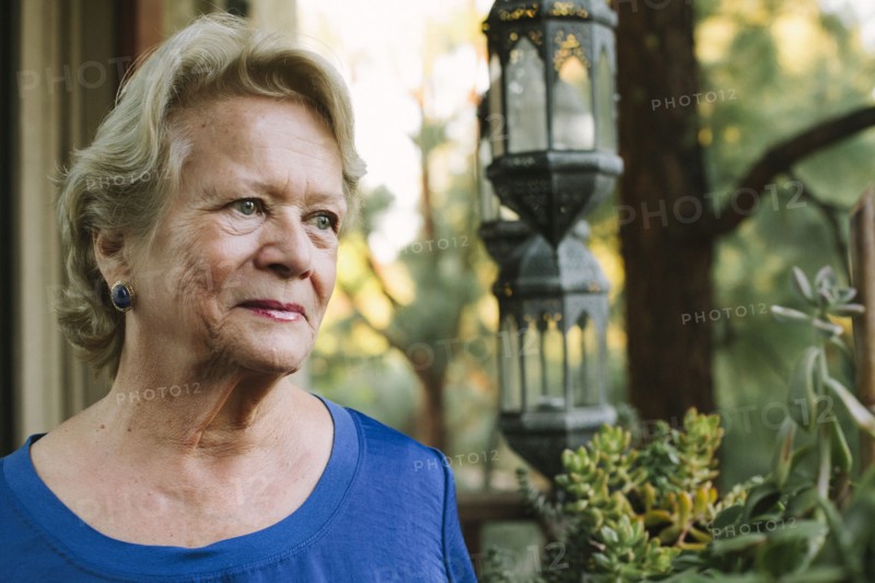 Pensive older woman standing on porch