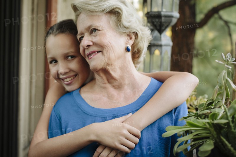 Grandmother and granddaughter hugging on porch