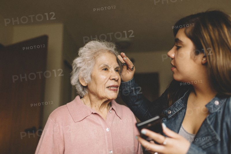 Granddaughter applying makeup on grandmother