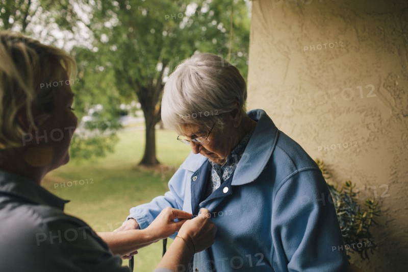 Older woman and granddaughter standing on balcony