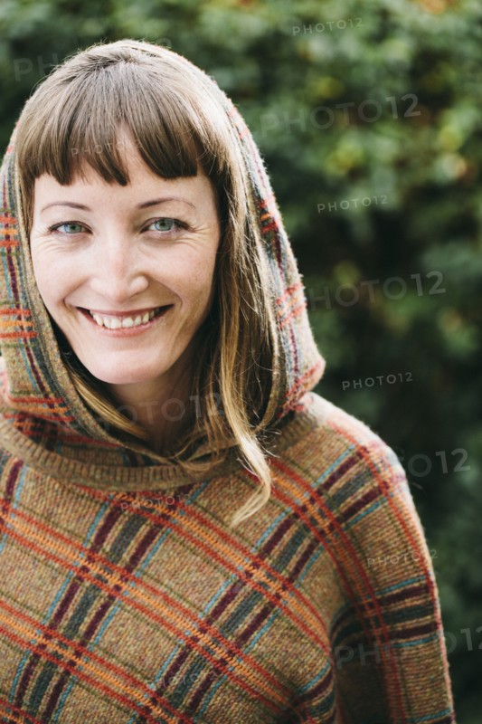 Mixed race woman wearing hood and shawl in backyard