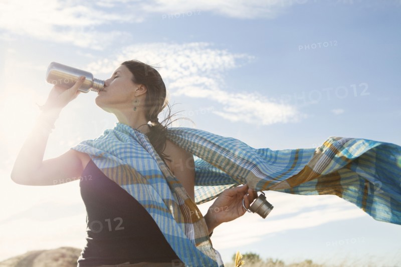 Caucasian woman drinking from bottle in wind