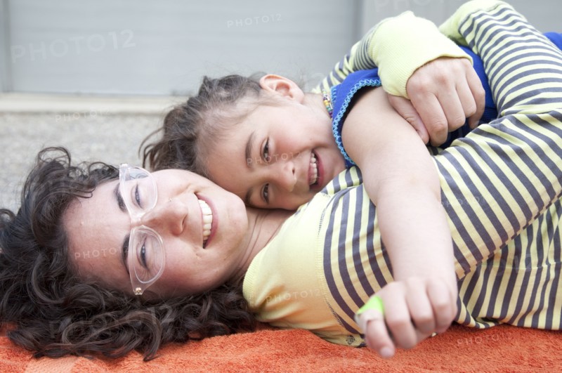 Caucasian mother and daughter hugging on carpet