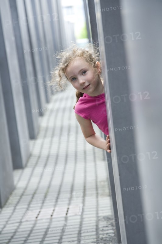 Caucasian girl peeking around corner in hallway