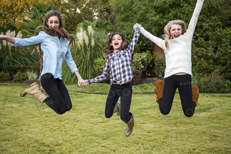 Caucasian teenage girls jumping for joy in backyard