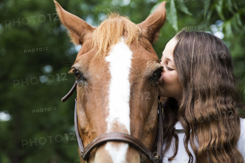 Teenage girl kissing face of horse