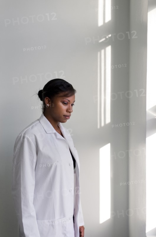 Serious doctor standing at window
