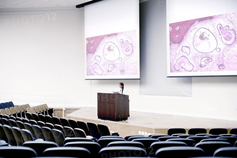 Armenian doctor speaking at podium in empty classroom