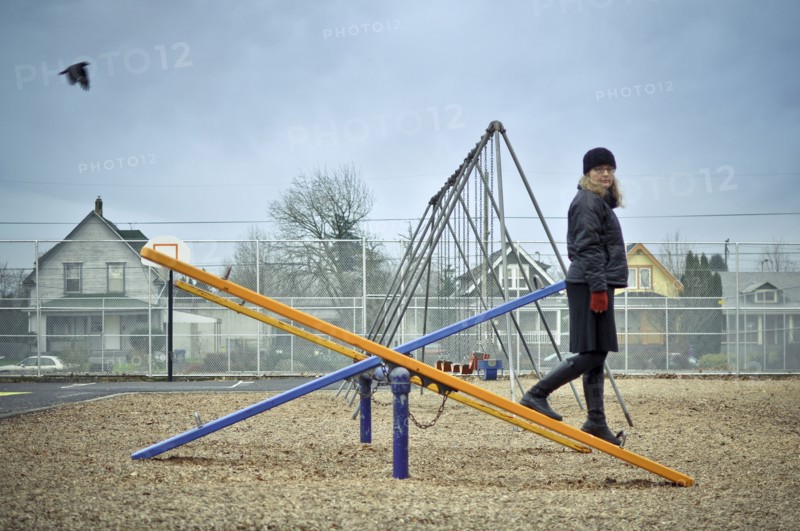 Caucasian woman walking on playground seesaw