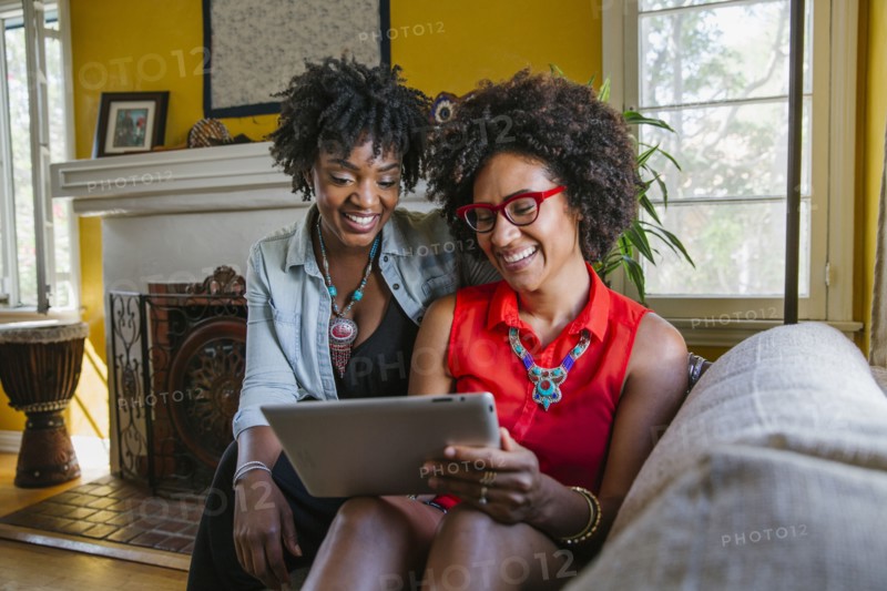Women using digital tablet on sofa