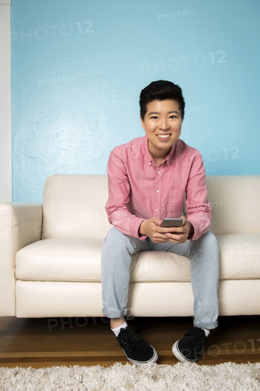 Androgynous woman using cell phone on sofa