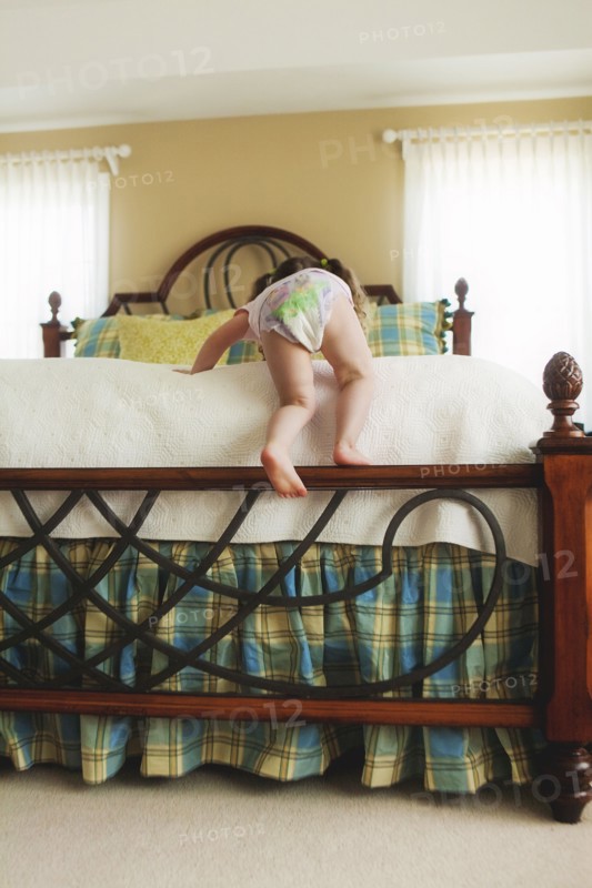 Rear view of baby girl climbing bed