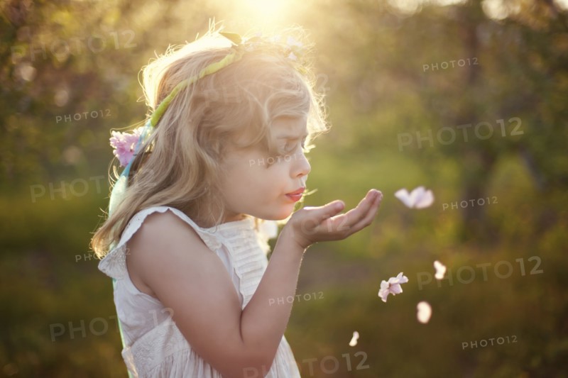 Caucasian girl blowing flower petals outdoors