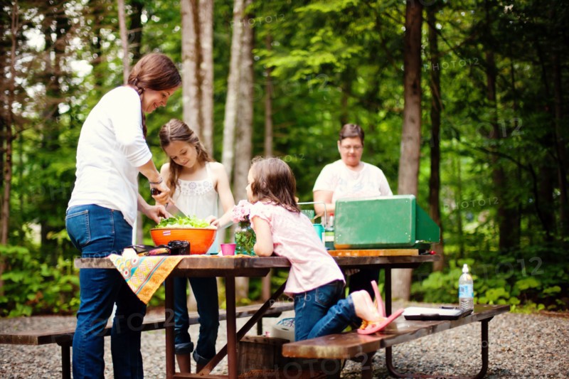 Three generations of Caucasian women cooking at picnic table
