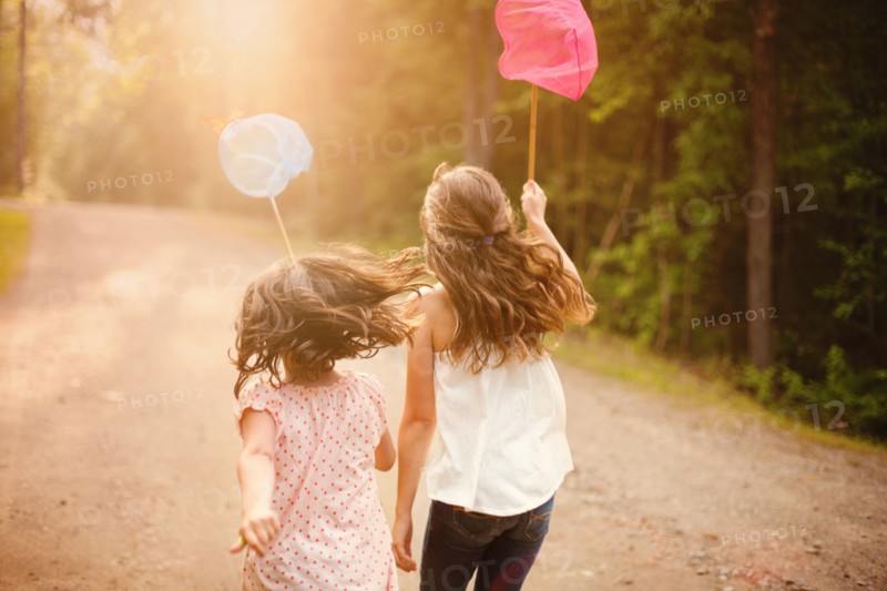 Caucasian girls carrying butterfly nets on dirt road