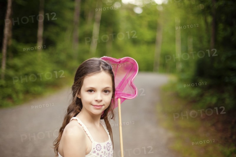 Caucasian girl carrying butterfly net on dirt road