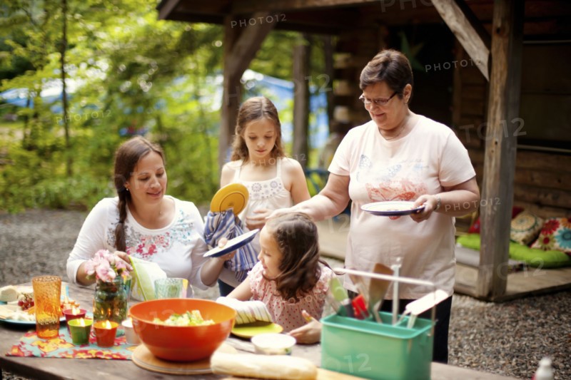 Three generations of Caucasian women cooking outside cabin