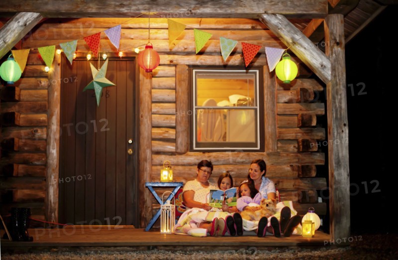 Three generations of Caucasian women reading on cabin porch