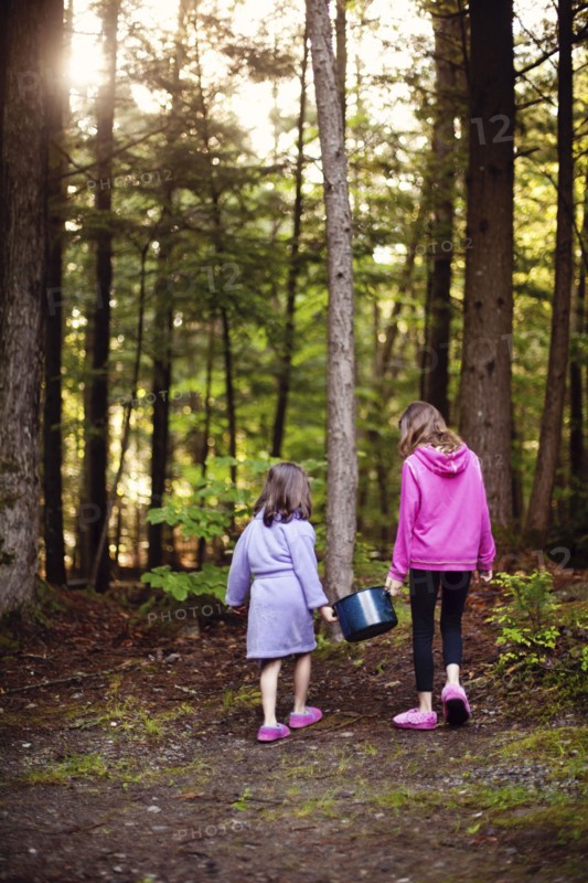 Caucasian girls carrying pot of water in forest