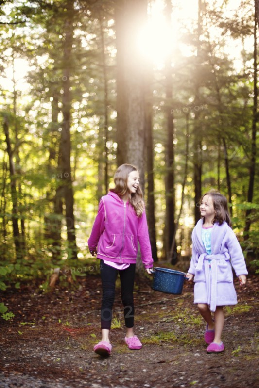 Caucasian girls carrying pot of water in forest