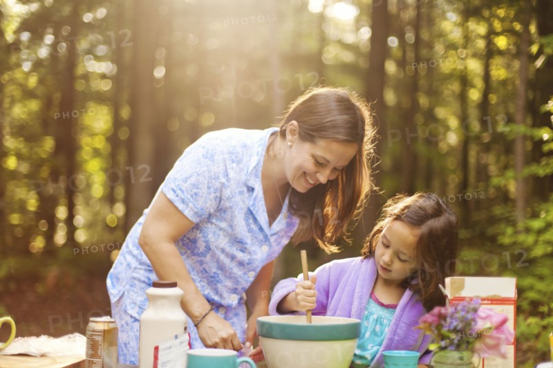 Caucasian mother and daughter cooking in forest