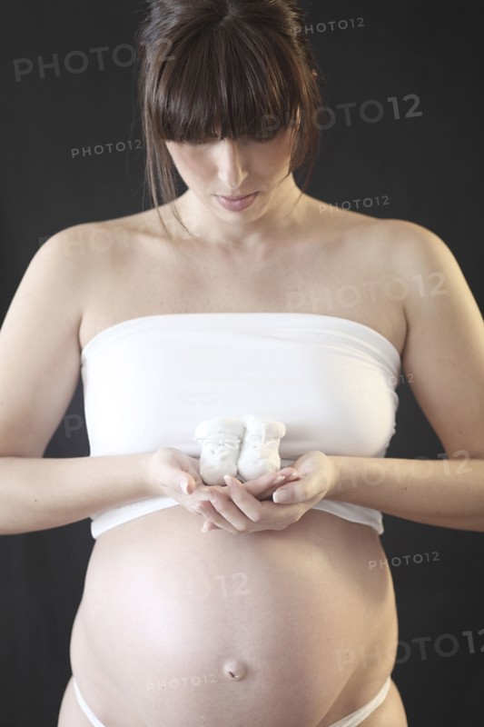 Pregnant Caucasian woman holding baby booties