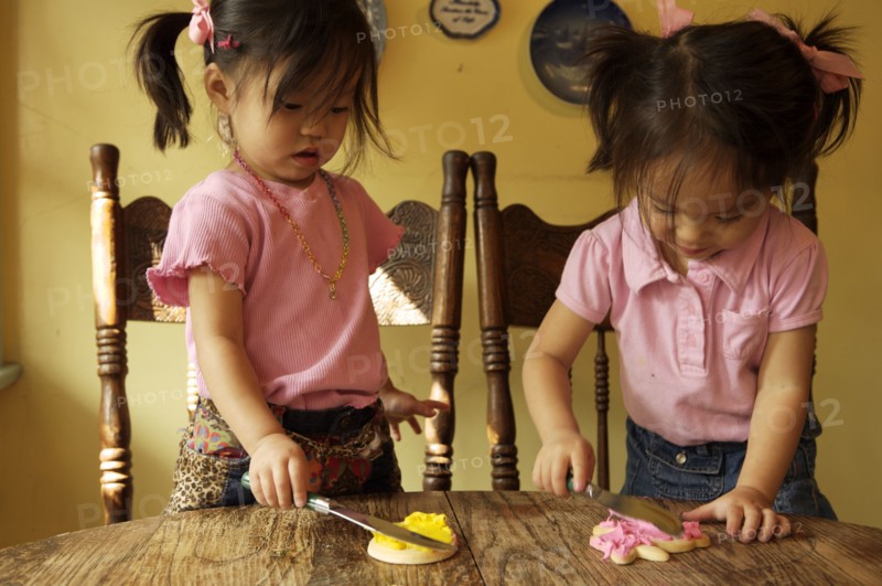Chinese twin girls making cookies at table