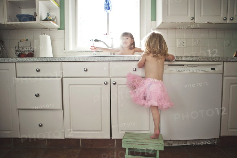 Sisters playing at kitchen sink
