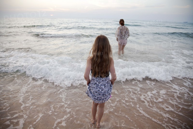 Women walking in ocean waves on beach
