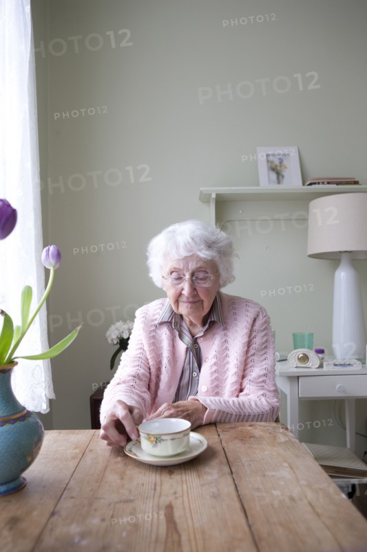 Older woman drinking tea at table
