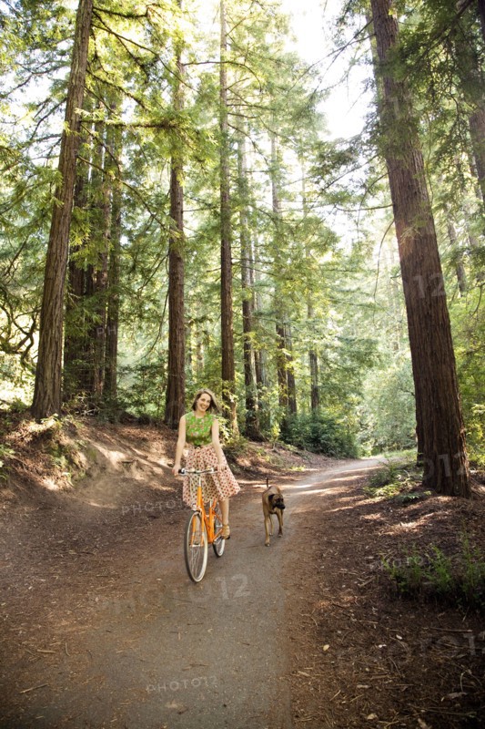 Mixed race woman riding bicycle with dog