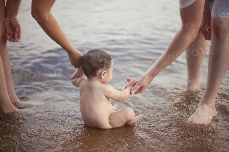 Parents helping baby sit in lake