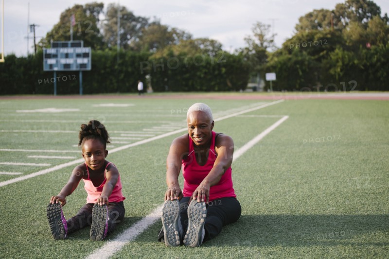 Grandmother and granddaughter stretching on football field