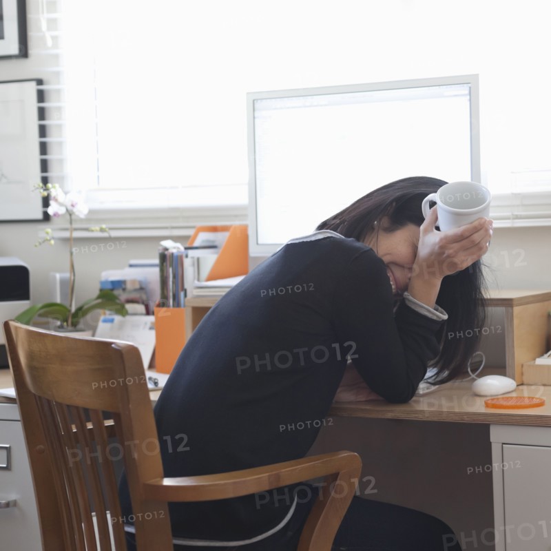 Hispanic woman working in home office drinking coffee