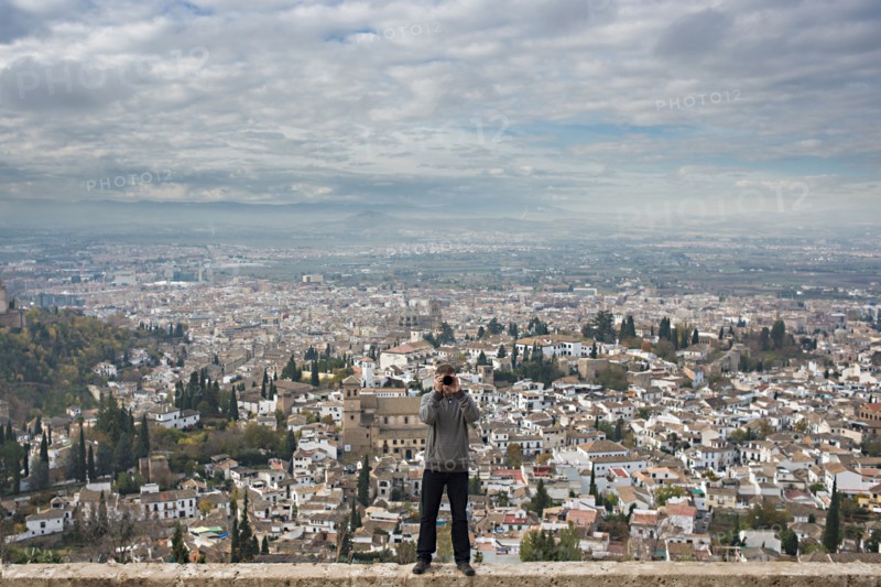 Caucasian tourist on wall over scenic view of cityscape