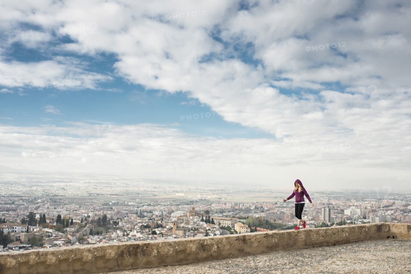 Caucasian woman on wall overlooking scenic view of cityscape