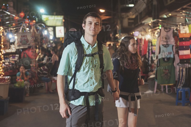 Caucasian tourists holding hands in market at night