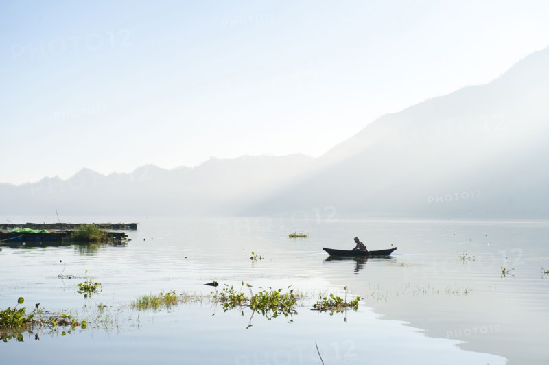 Man rowing canoe on still remote lake
