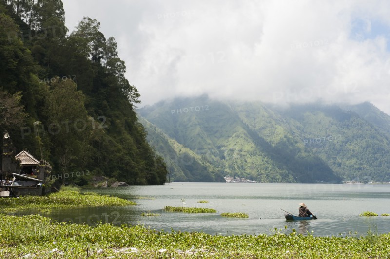 Fisherman rowing canoe on still rural lake