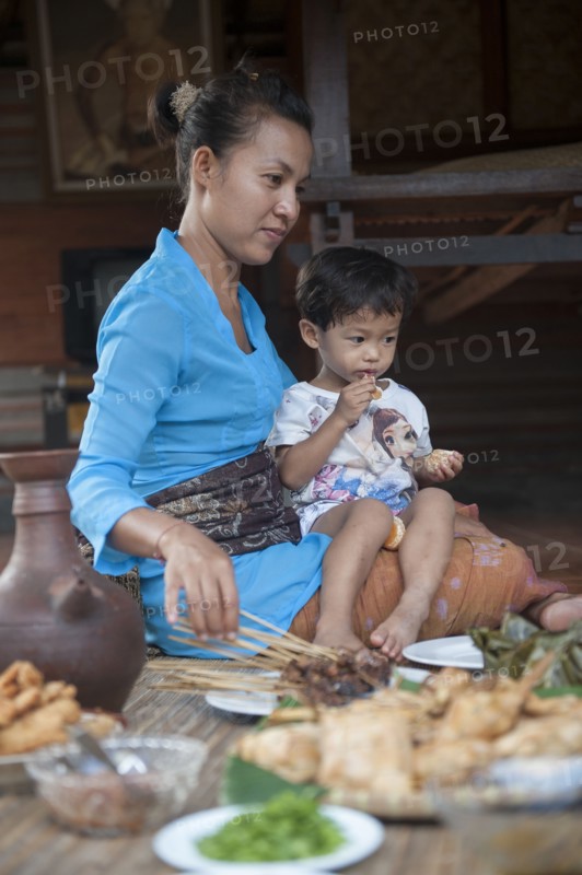 Asian mother and son eating on woven mat