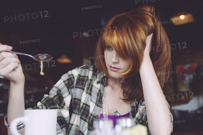 Caucasian woman playing with coffee in cafe