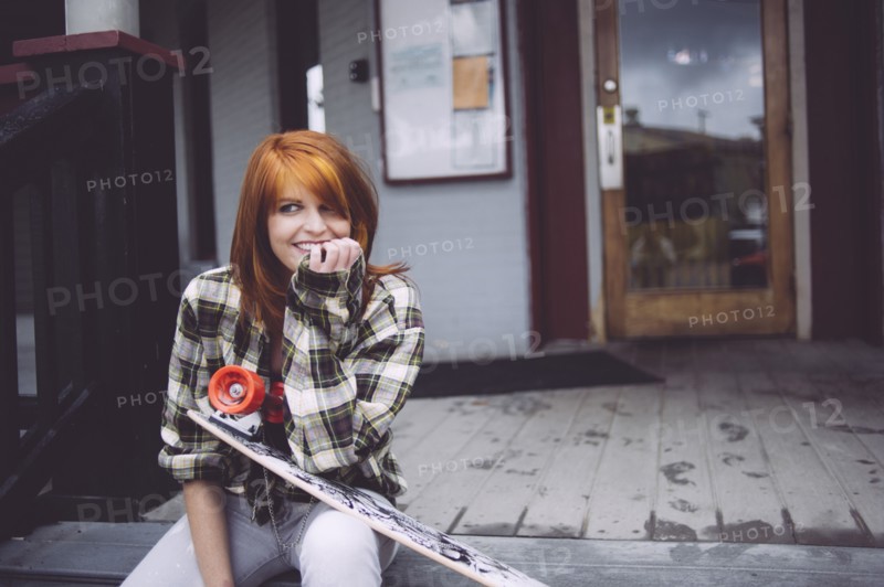 Caucasian woman holding skateboard on patio