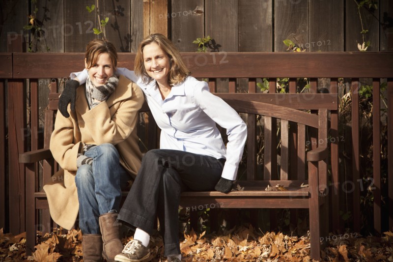 Caucasian friends sitting on bench in autumn