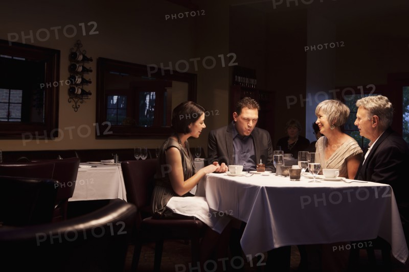 Friends watching man blow out birthday cupcake in restaurant