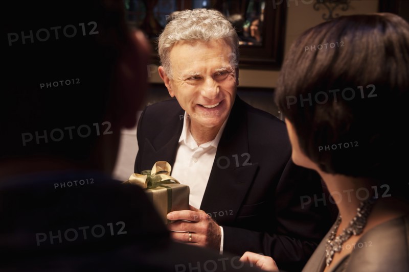 Caucasian man giving woman gift in restaurant