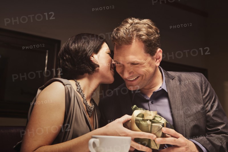 Caucasian man giving woman gift in restaurant