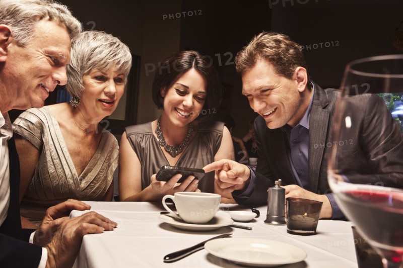 Friends looking at camera phone in restaurant