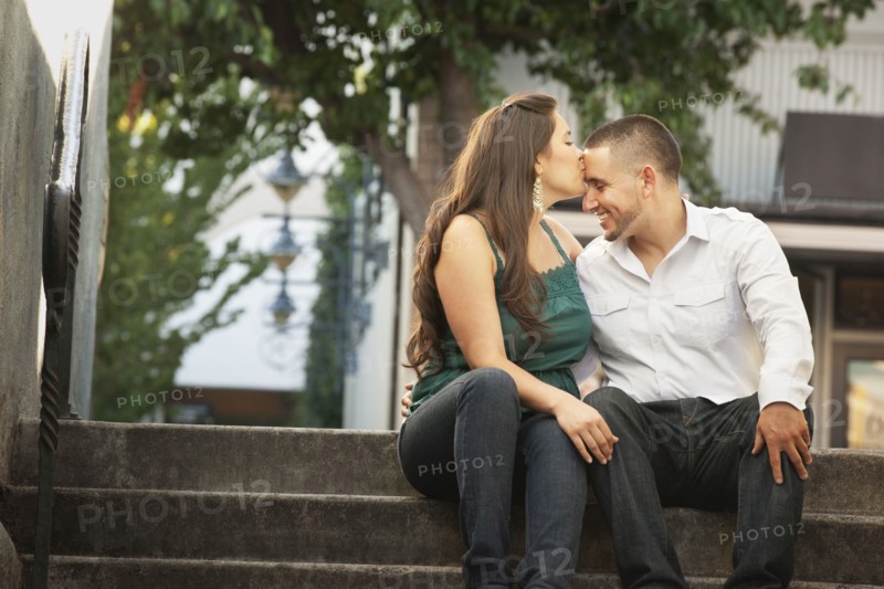 Hispanic woman kissing husband on forehead